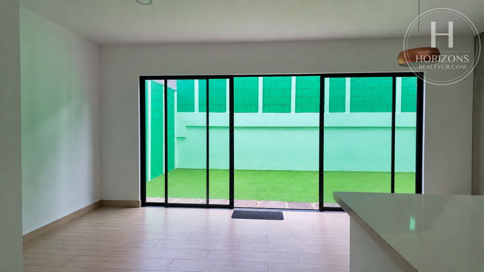 Sala con puertas corredizas de vidrio hacia el patio – Casa en Condominio Bali, Guachipelín de Escazú | Horizons Realty